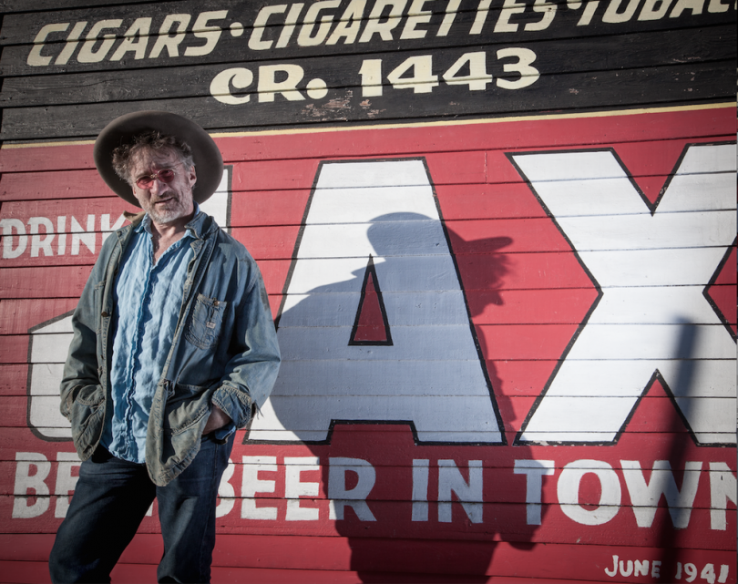 Photograph of Jon Cleary standing in front of Red sign