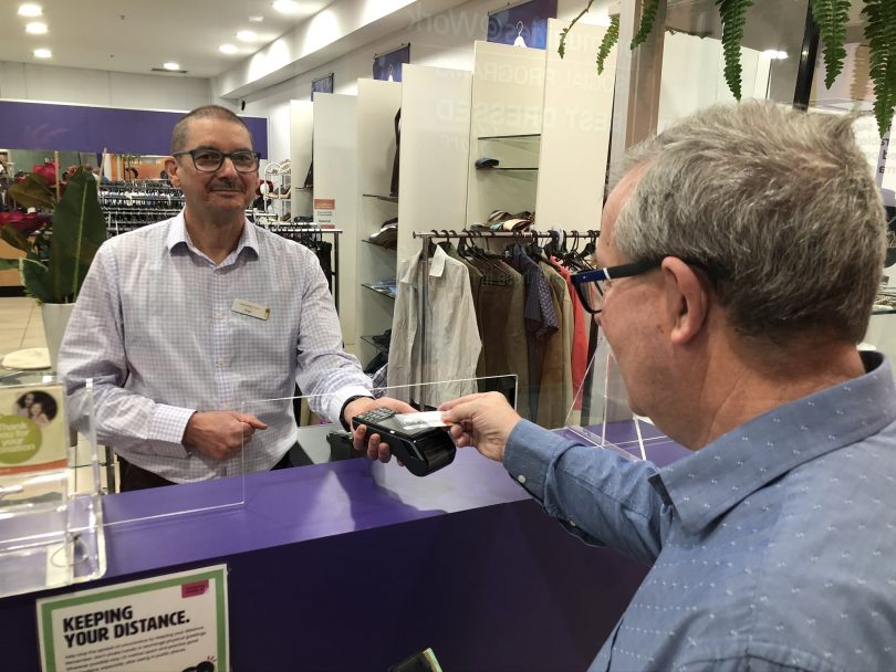 Man making purchase at counter at Communities@Work's Best Dressed Store in Tuggeranong.