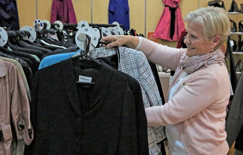 Woman holding jacket for sale at Best Dressed Store op shop.