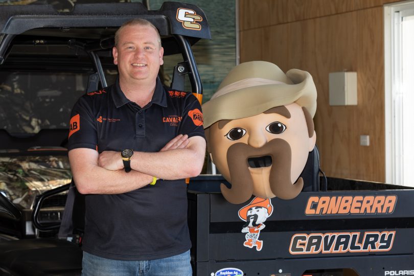 Josh Williams standing next to Sarge mascot outfit for Canberra Cavalry.