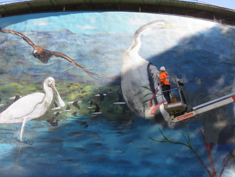 Street artist paints water tower