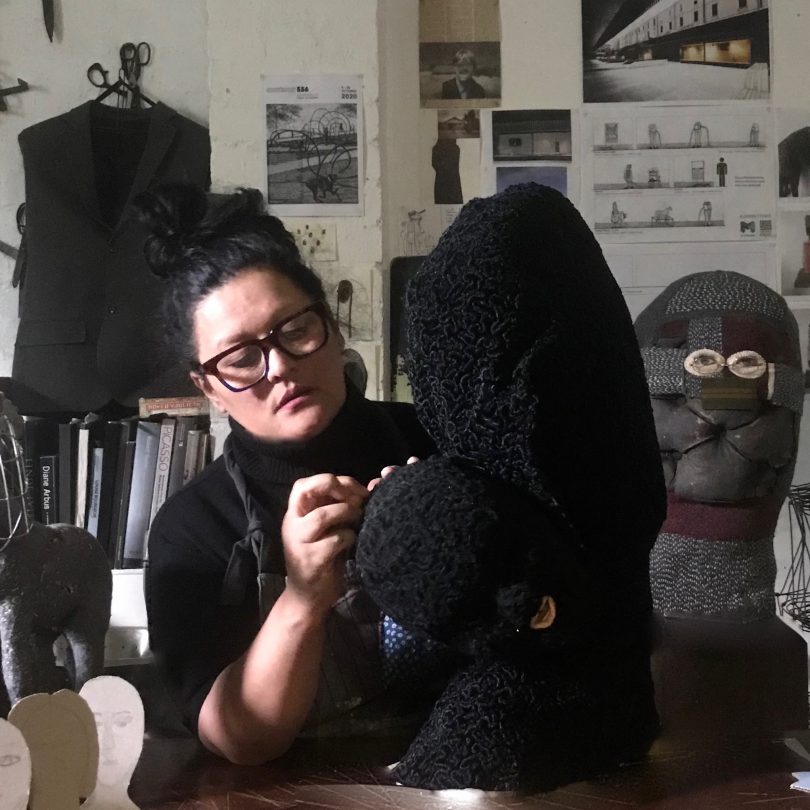 Visual artist Mariana del Castillo hand stitching large black sculpture.