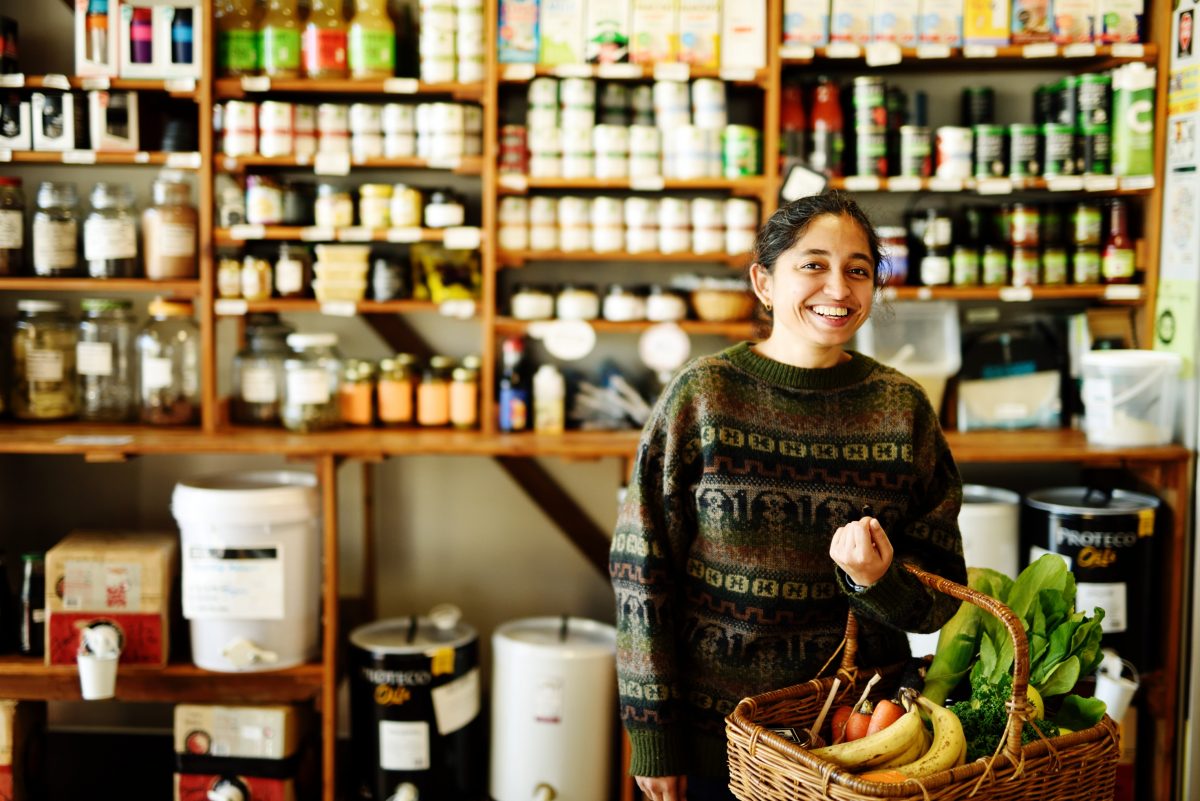 lady in the food co-op smiling with a basket of food