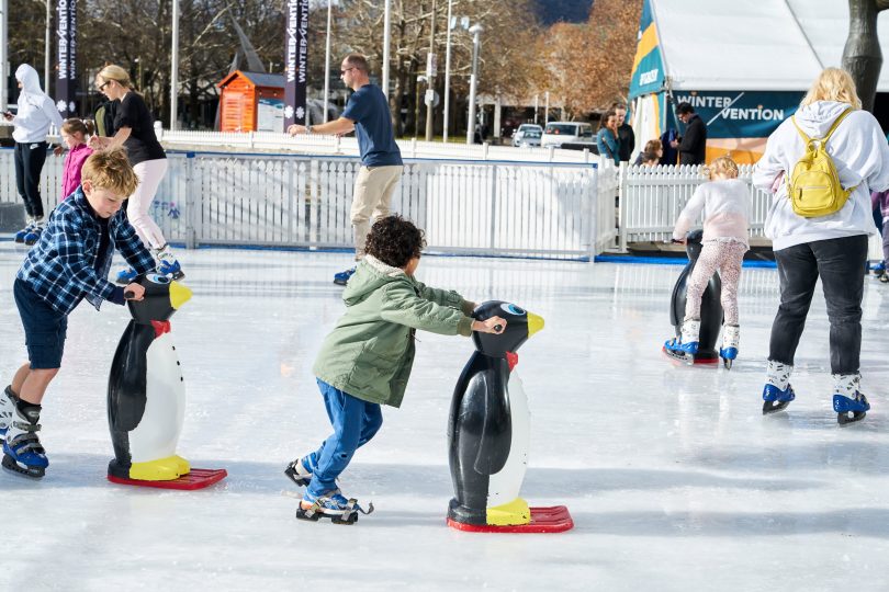 boy pushing penguin on ice