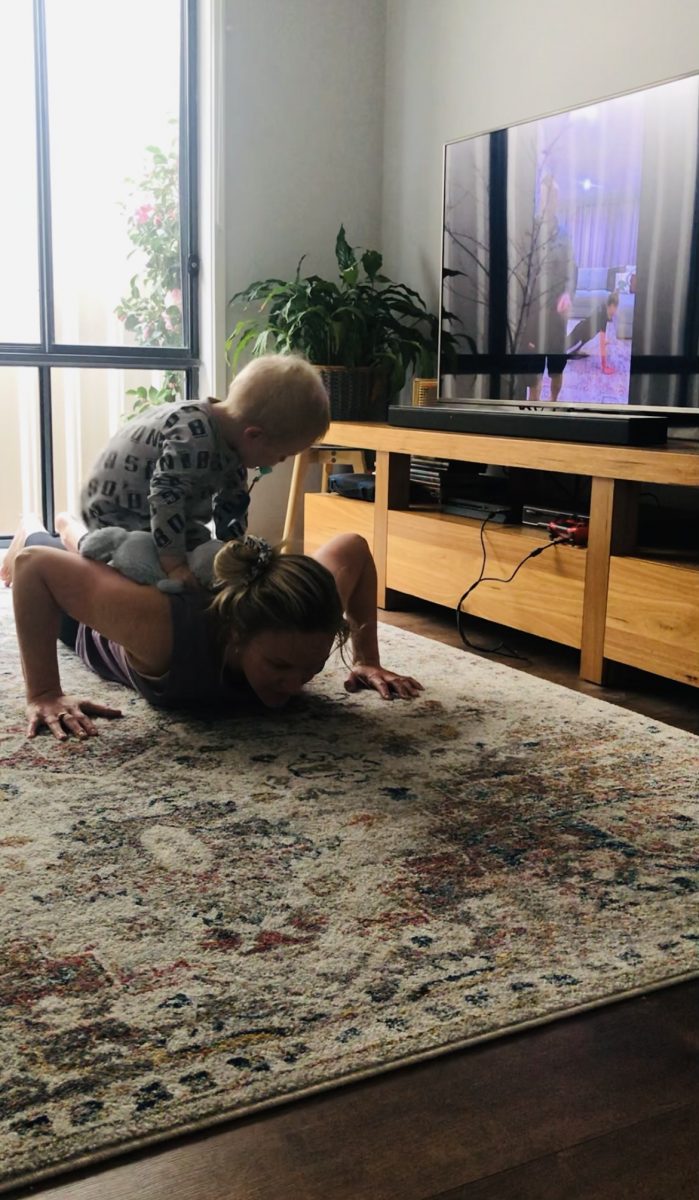 Woman doing a push-up at home with toddler on her back