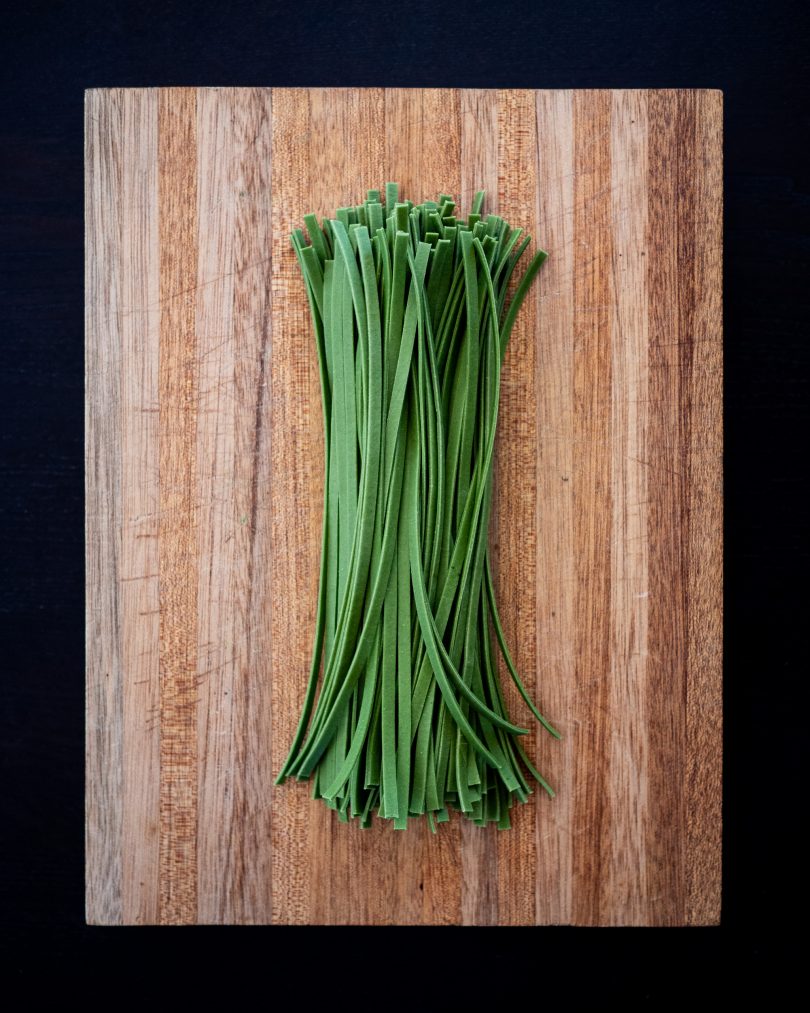 Green pasta on a wooden board