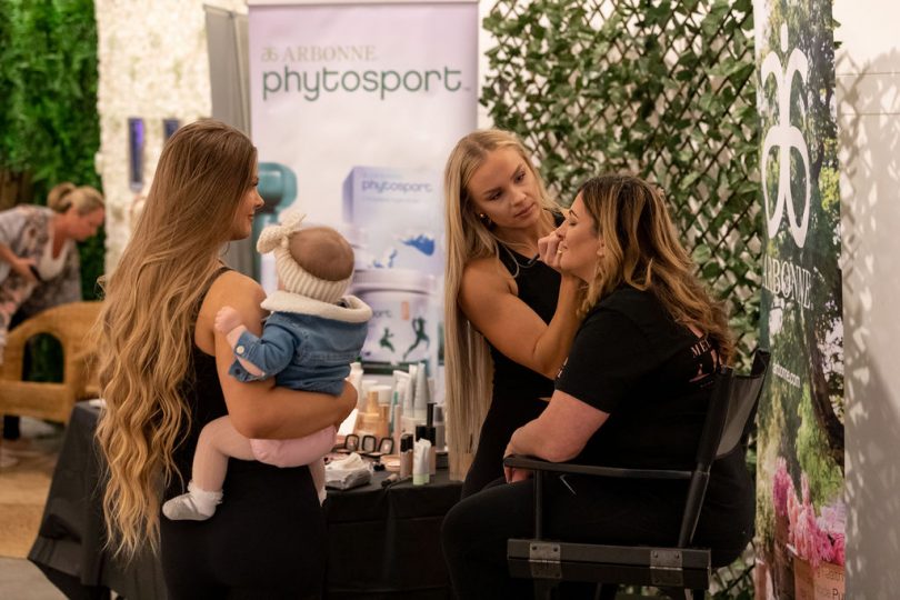 Woman applying makeup to lady in chair at Arbonne event