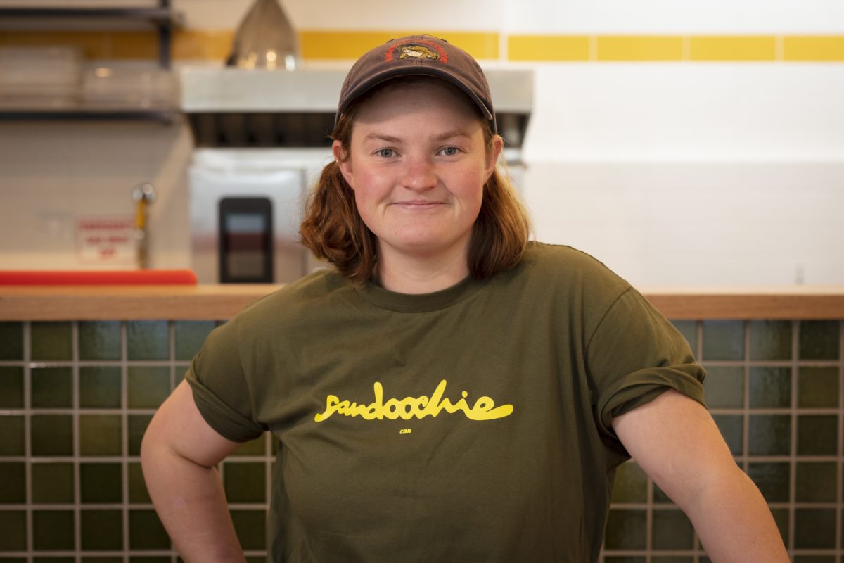 Lucy wears a branded sandoochie tshirt and a cap