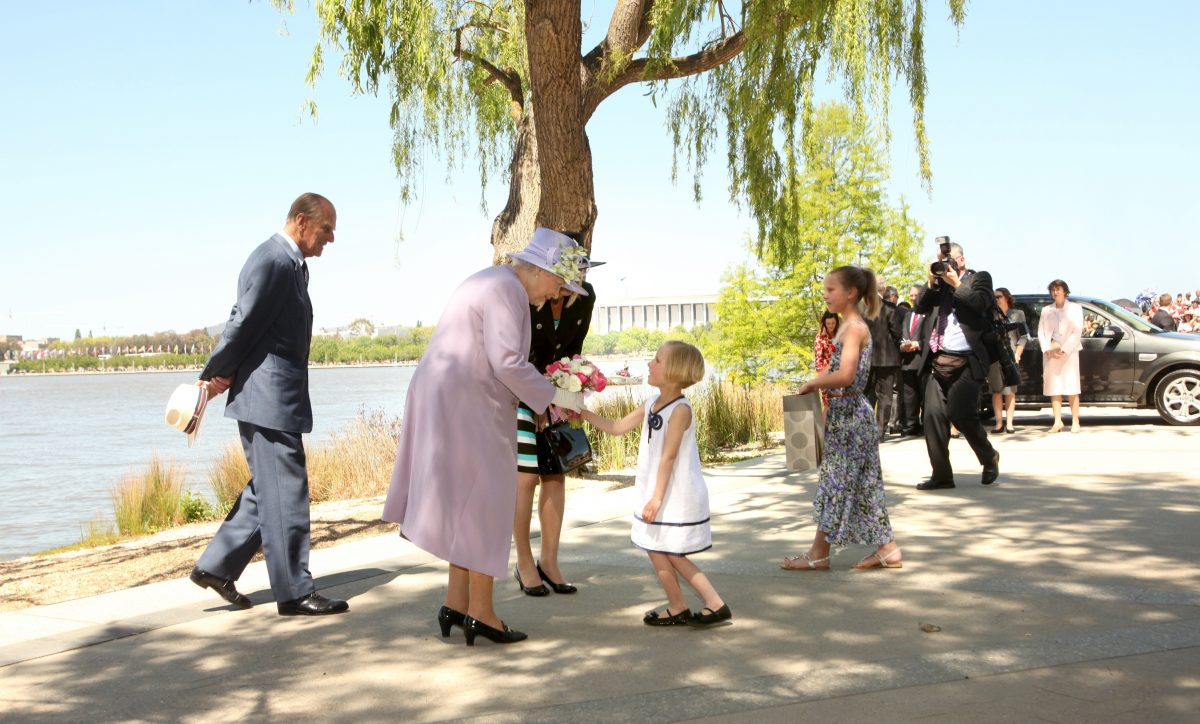 Queen accepts flowers from little girl.
