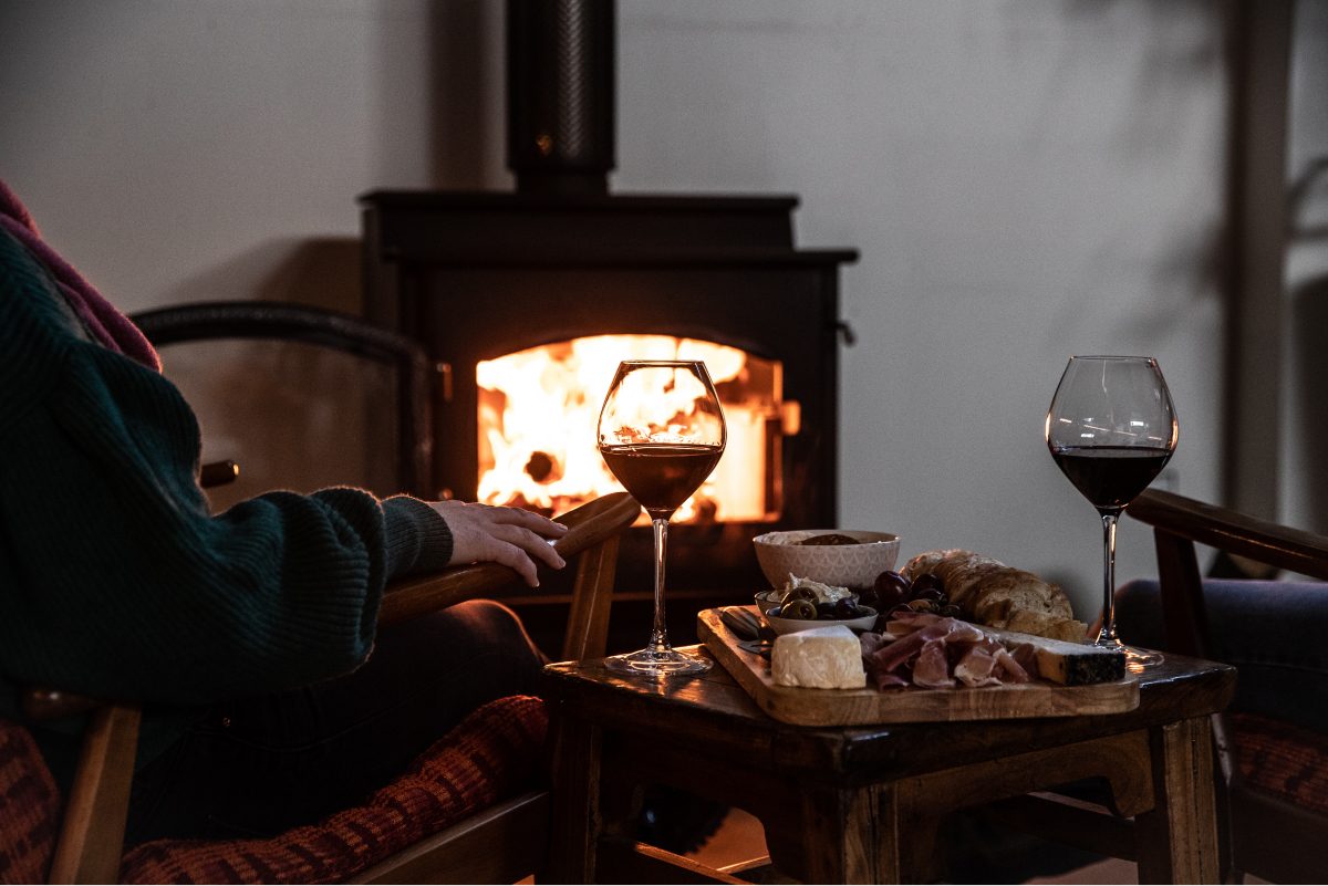 Glasses of wine and a cheese platter by a fireside