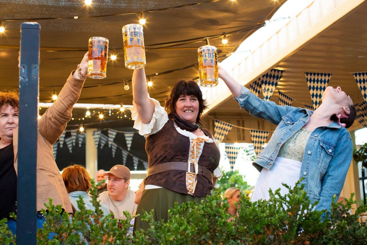people holding steins of beer in the air