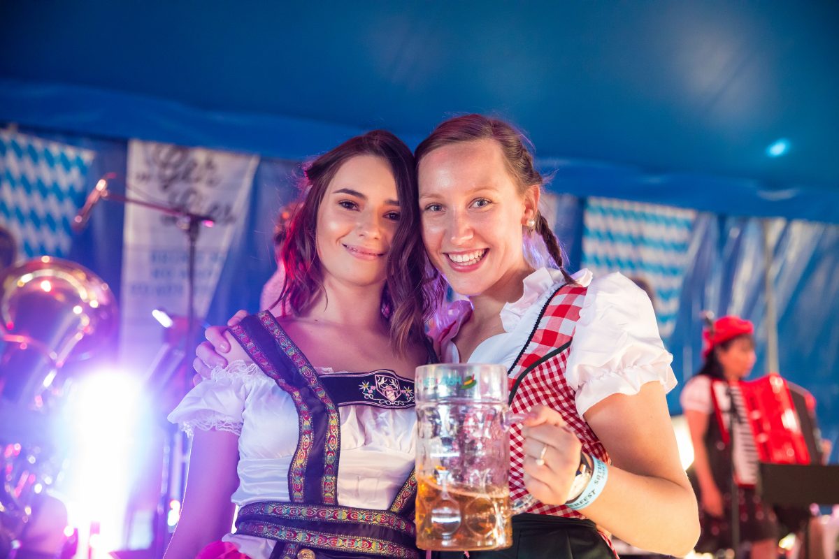 Two women in traditional German garb, one holding a stein of beer
