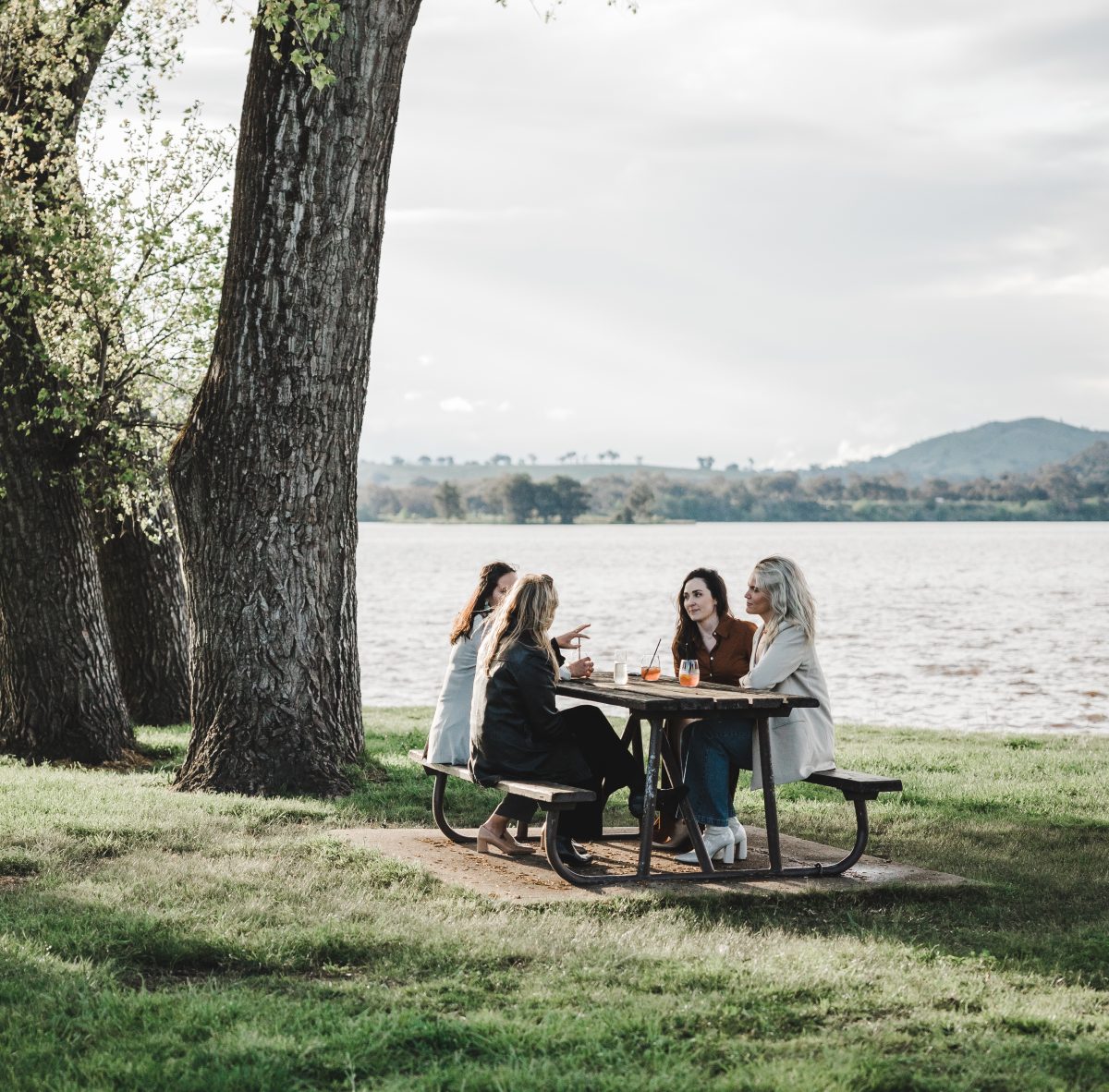 Women enjoy cold beverages from Snapper and Co at a bench by Lake Burley Griffin 