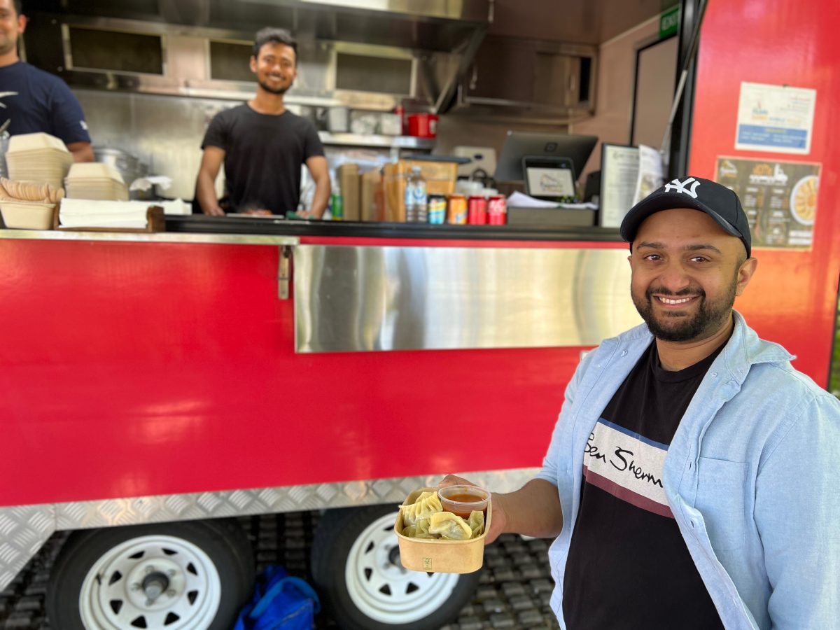 Two men smiling with red food truck