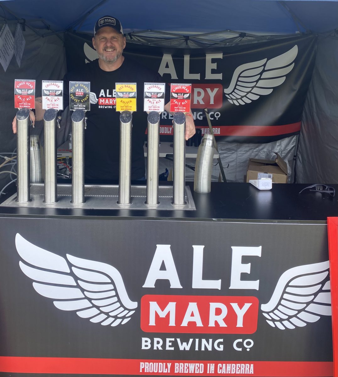 man standing behind Ale Mary logo with beer taps
