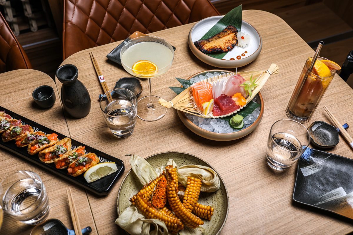 Table with sashimi, grilled corn and taco dishes