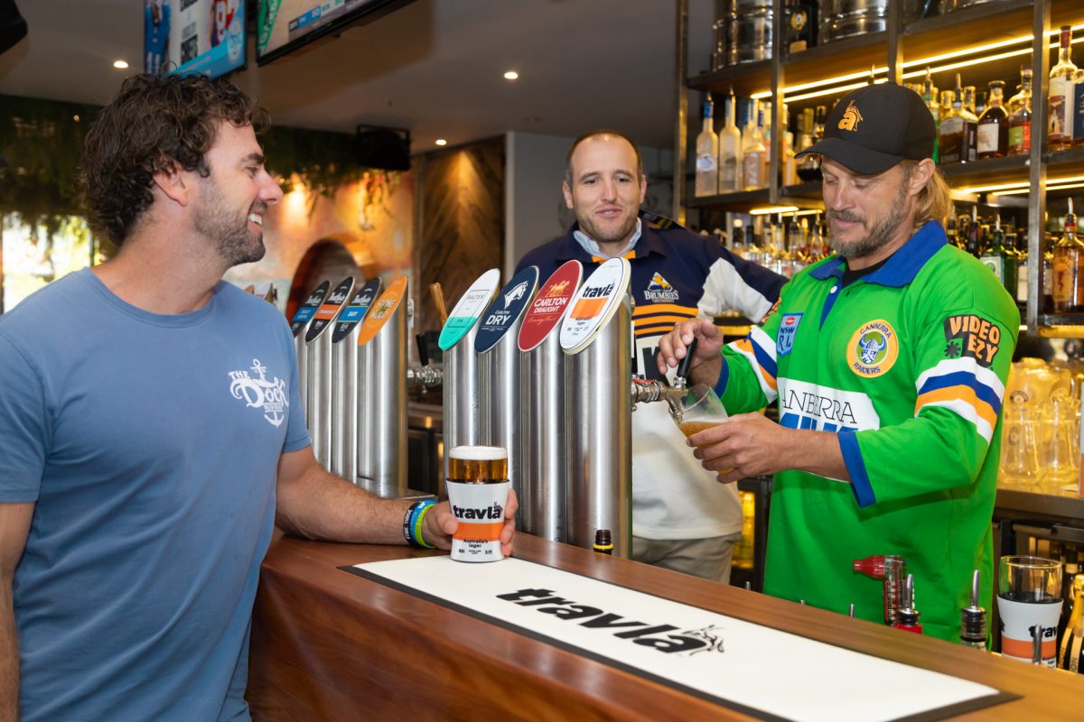 man pouring a beer behind a bar
