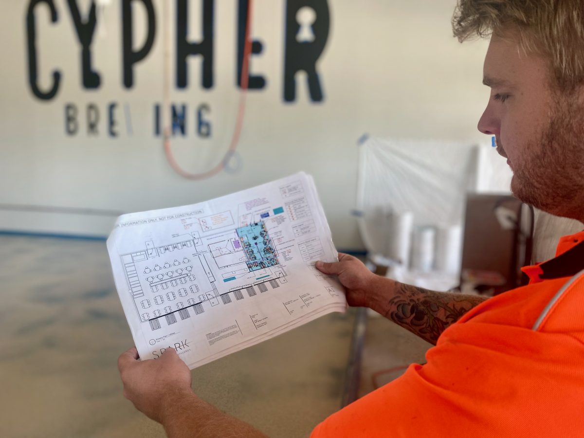 Jeff, wearing high vis, studies the Cypher Brewing Co. architectural plans