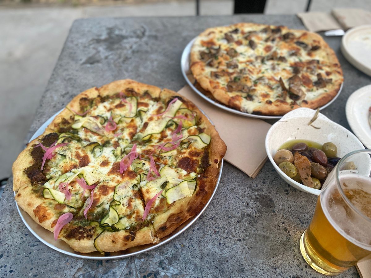 Pizzas, olives and a beer on the table at Gang Gang