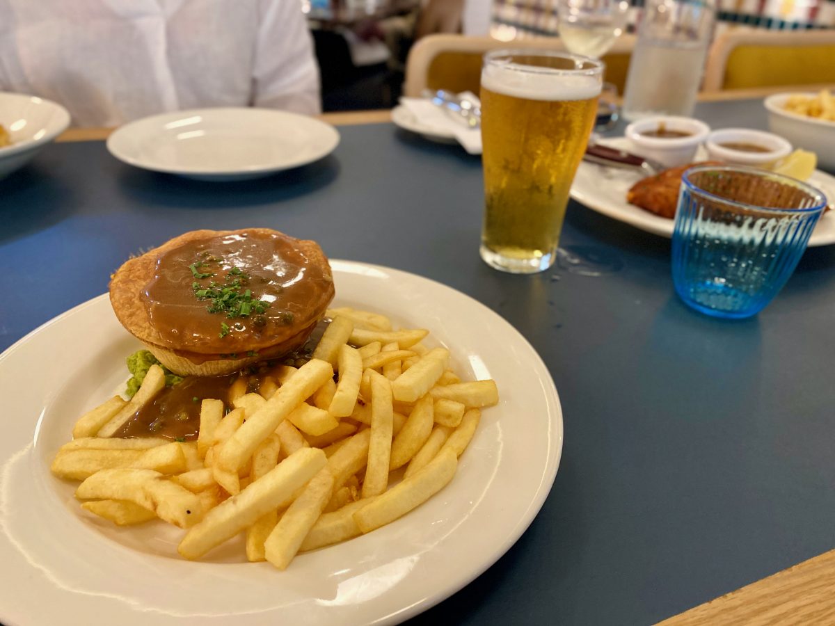 Plate with pie, gravy and chips with schooner of beer in background
