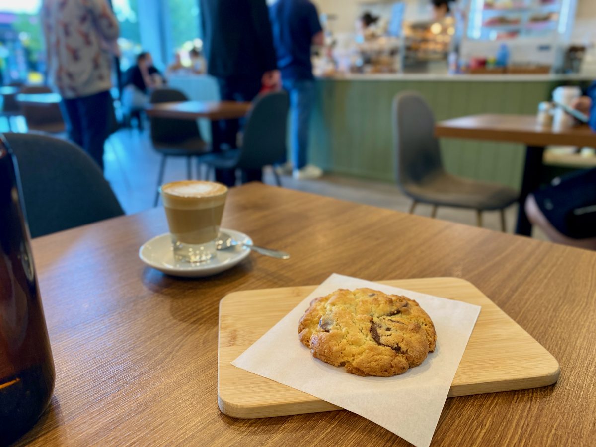 Chocolate chip cookie with coffee in the background.