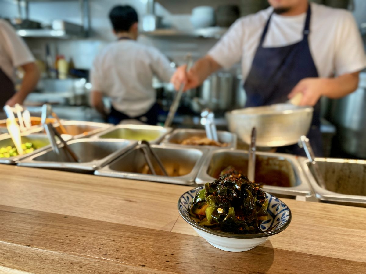 A bowl of pickles next to the kitchen pass at Canteen.