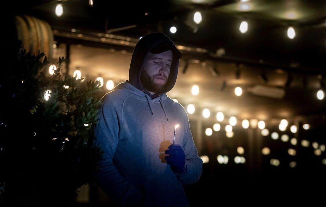 Man holding candle in dark at The Dock's ANZAC Day service.