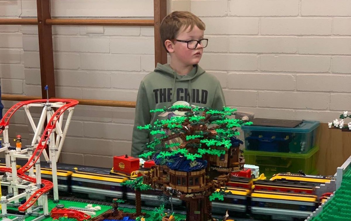 Child standing next to LEGO creation
