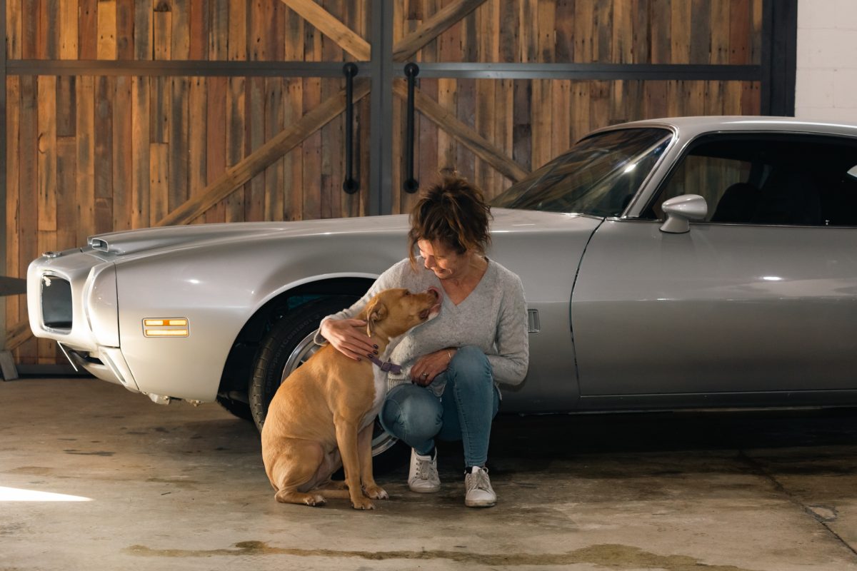 a woman with a dog next to a silver car