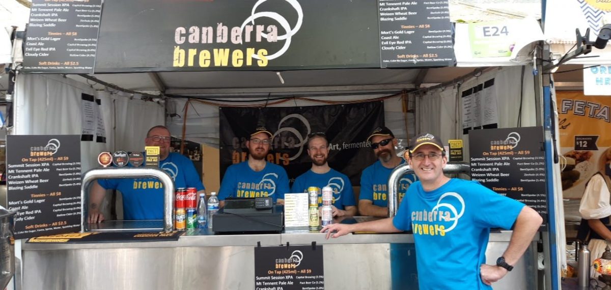 people in t-shirts under a Canberra Brewers marquee