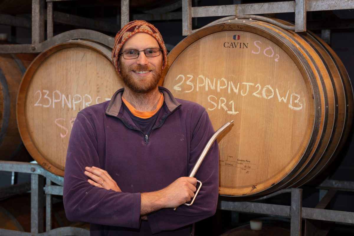 Jacob Law standing in front of wine barrel