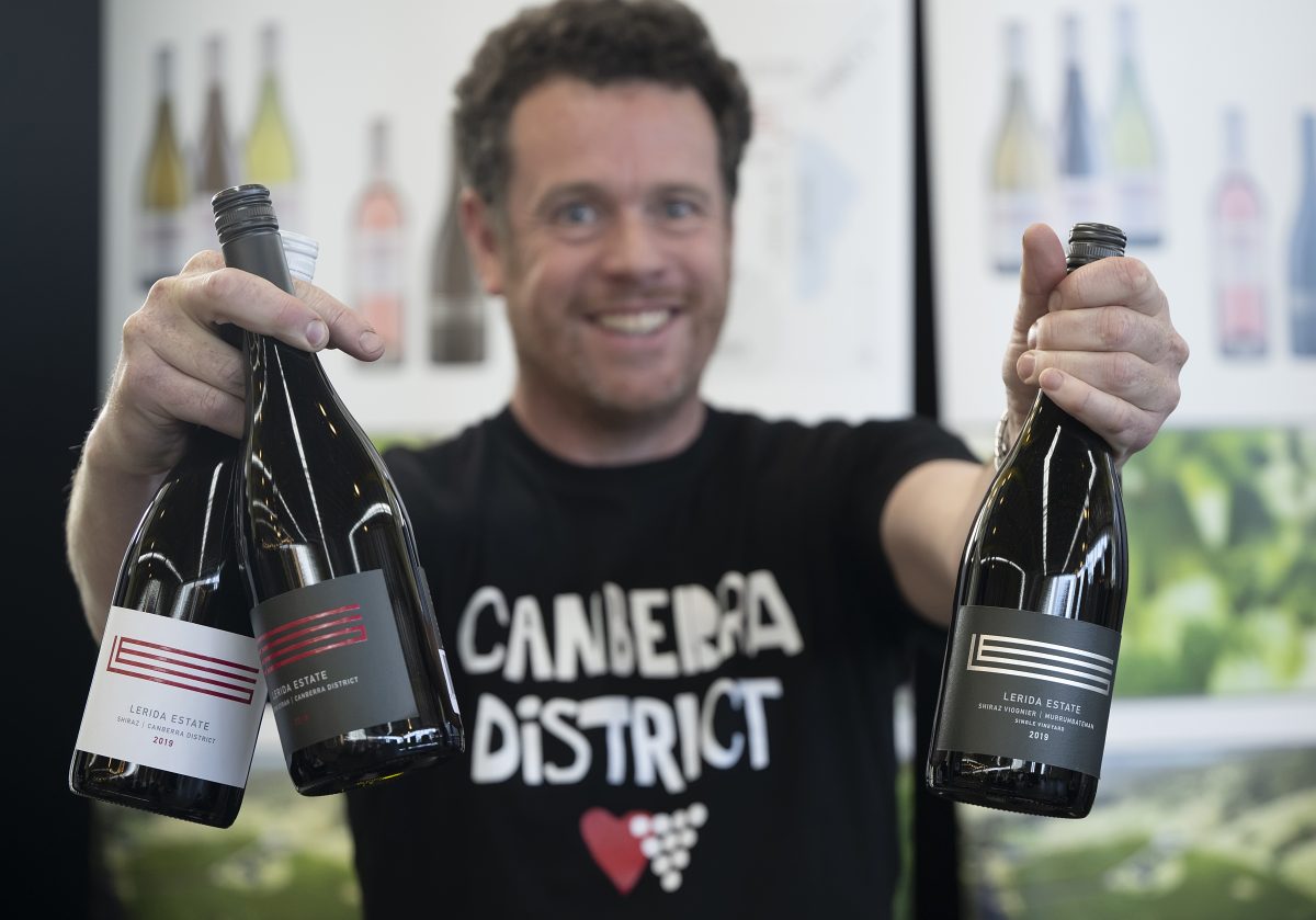Winemaker Andrew McFadzean holds out three bottles of wine