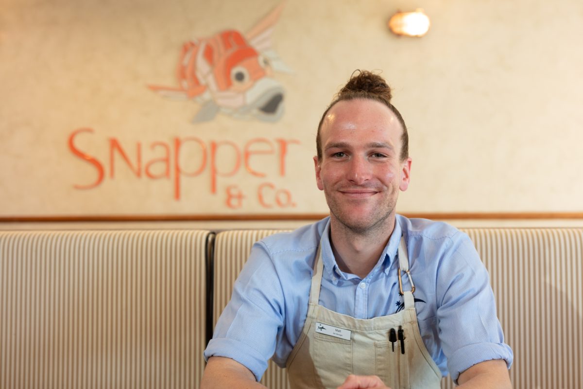 A man sitting in front of a Snapper and Co sign