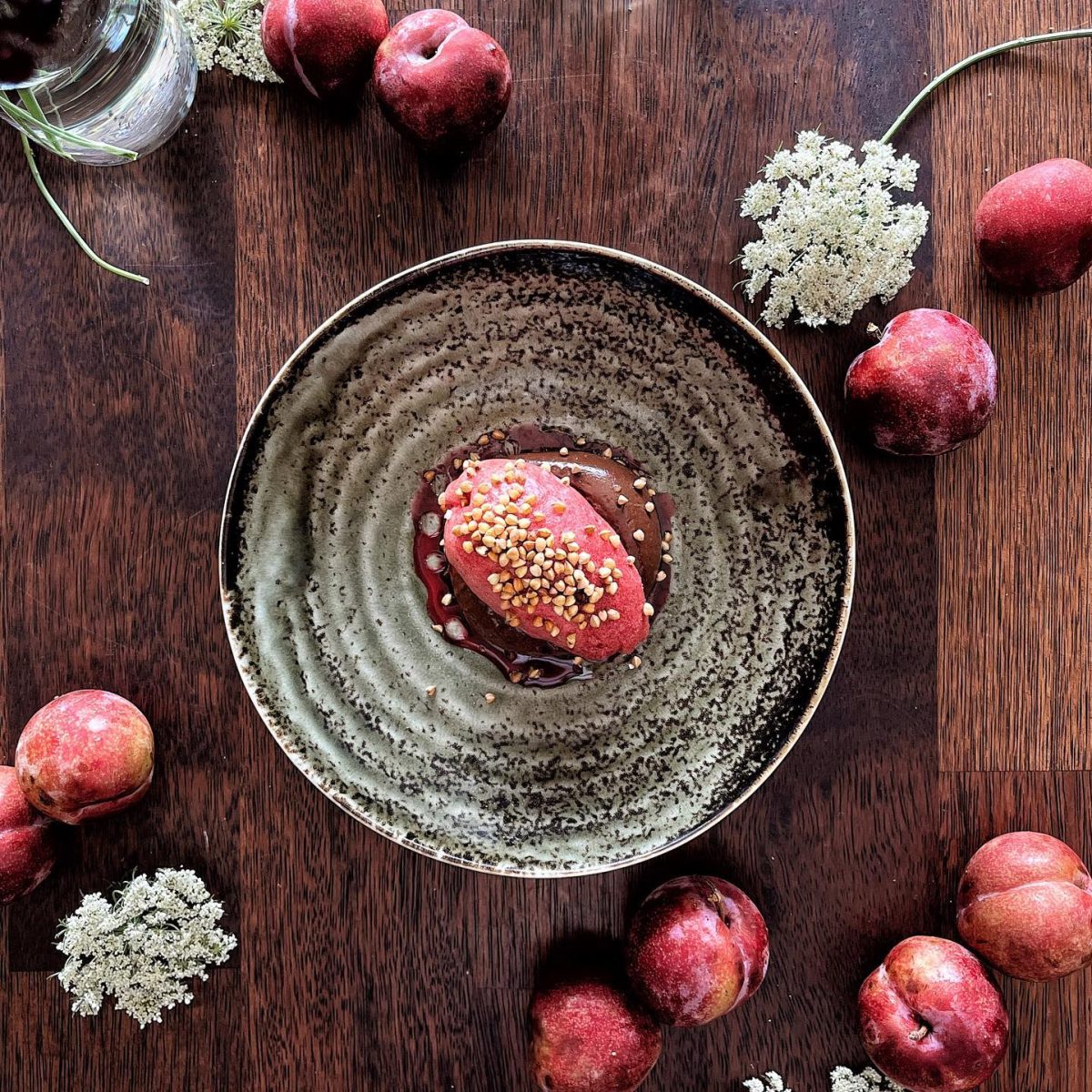 Plum sorbet on plate surrounded by plums.