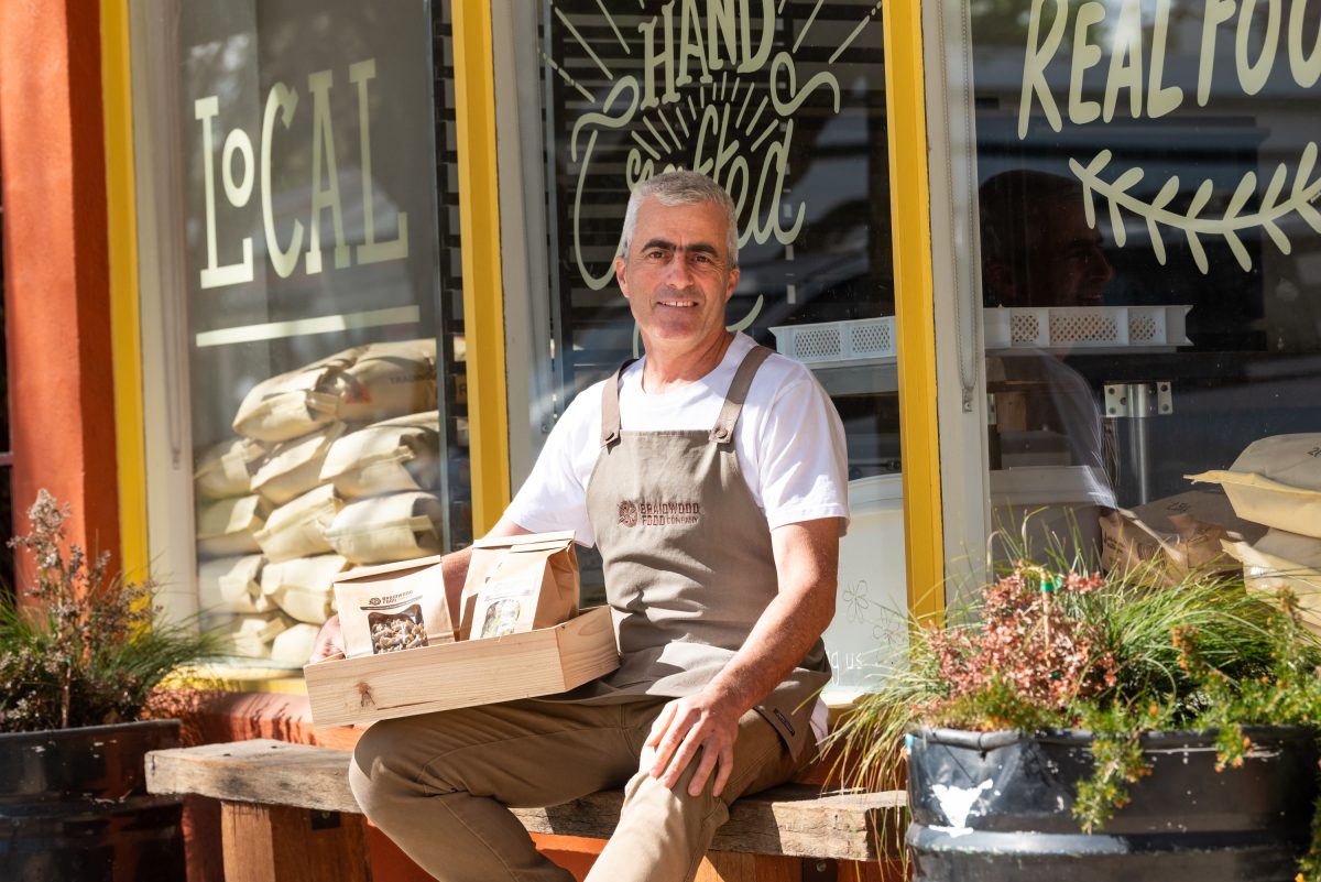 Tim sits outside his shop holding packets of pasta