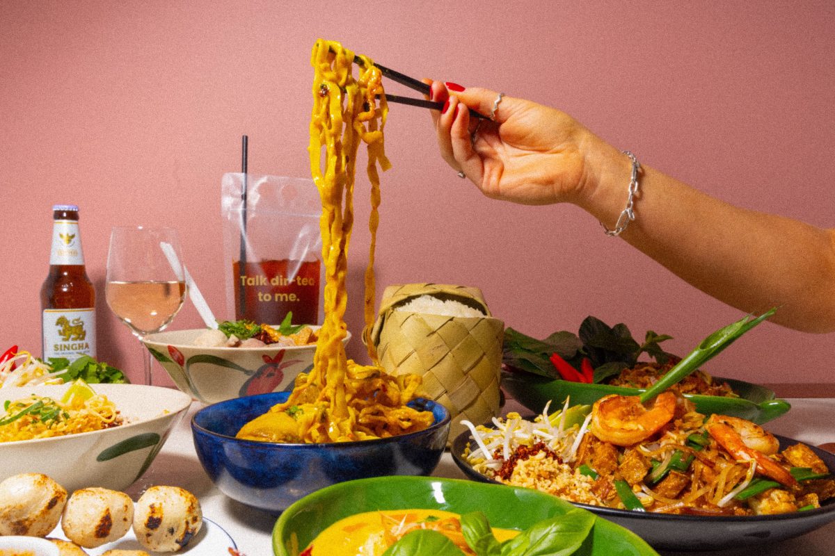 a hand holding chopsticks pulls up noodles from a bowl. 