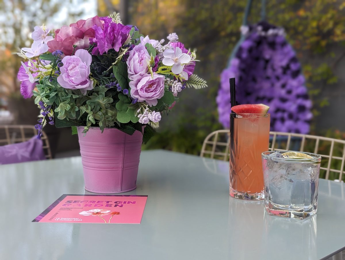 Two cocktails next to a purple flowerpot with colourful flowers