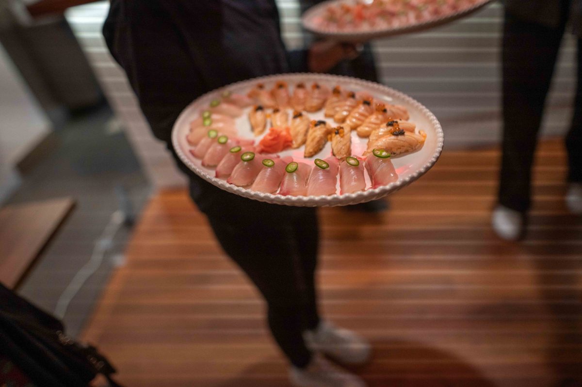 Server holding a plate of kingfish nigiri