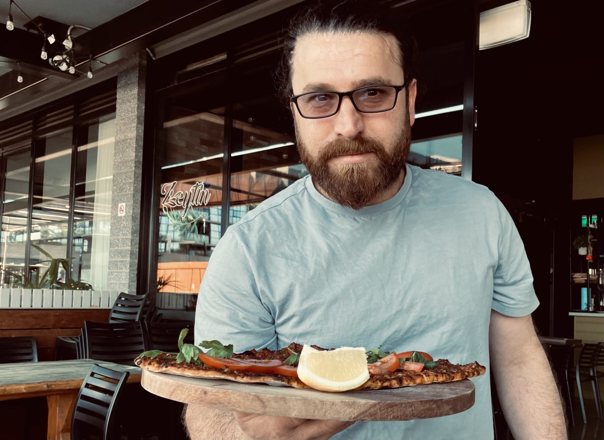 Man in dark glasses serving up a board of food.