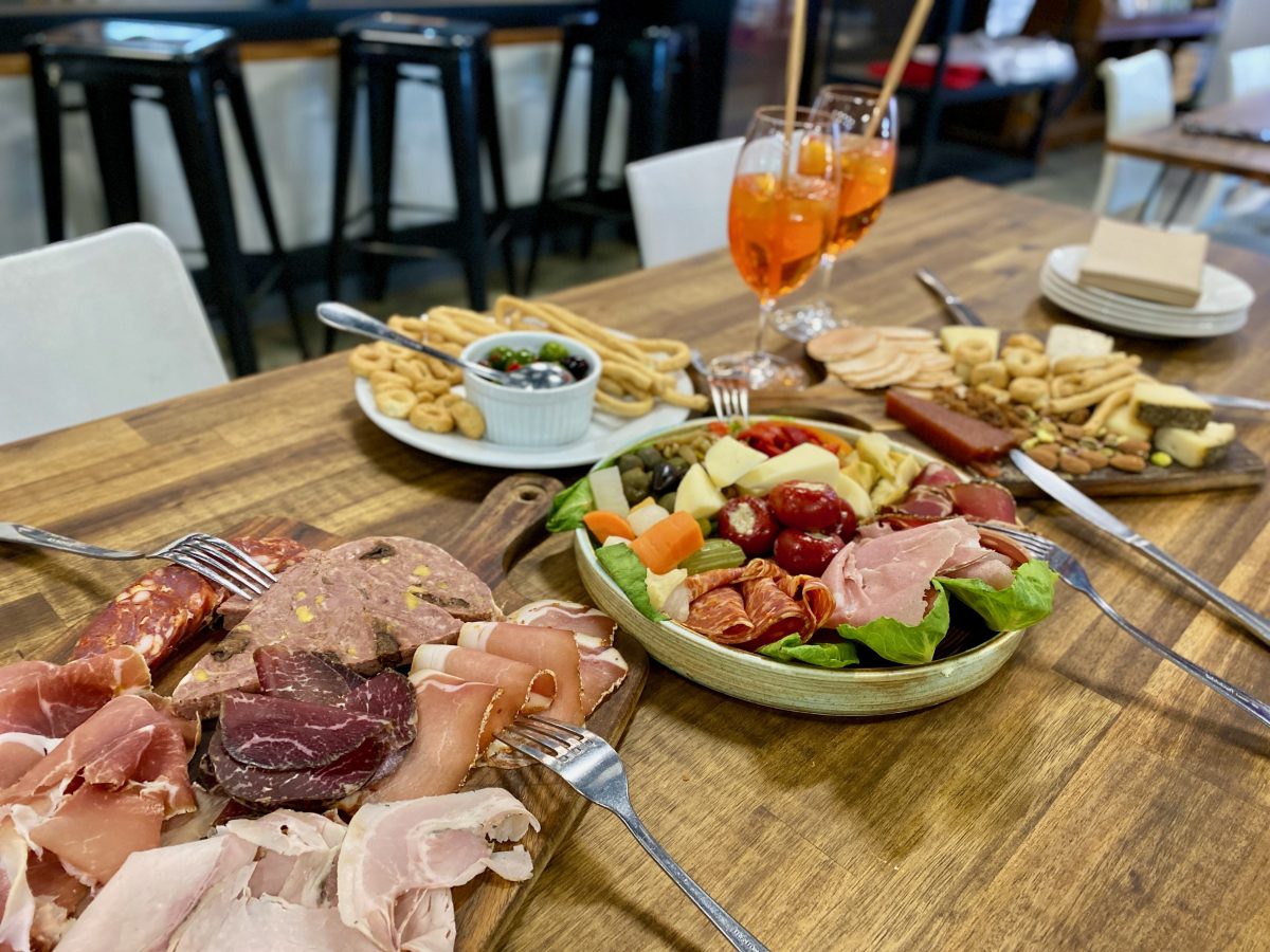 A table laid with multiple platters of cured meats, antipasto, cheese and nibbles
