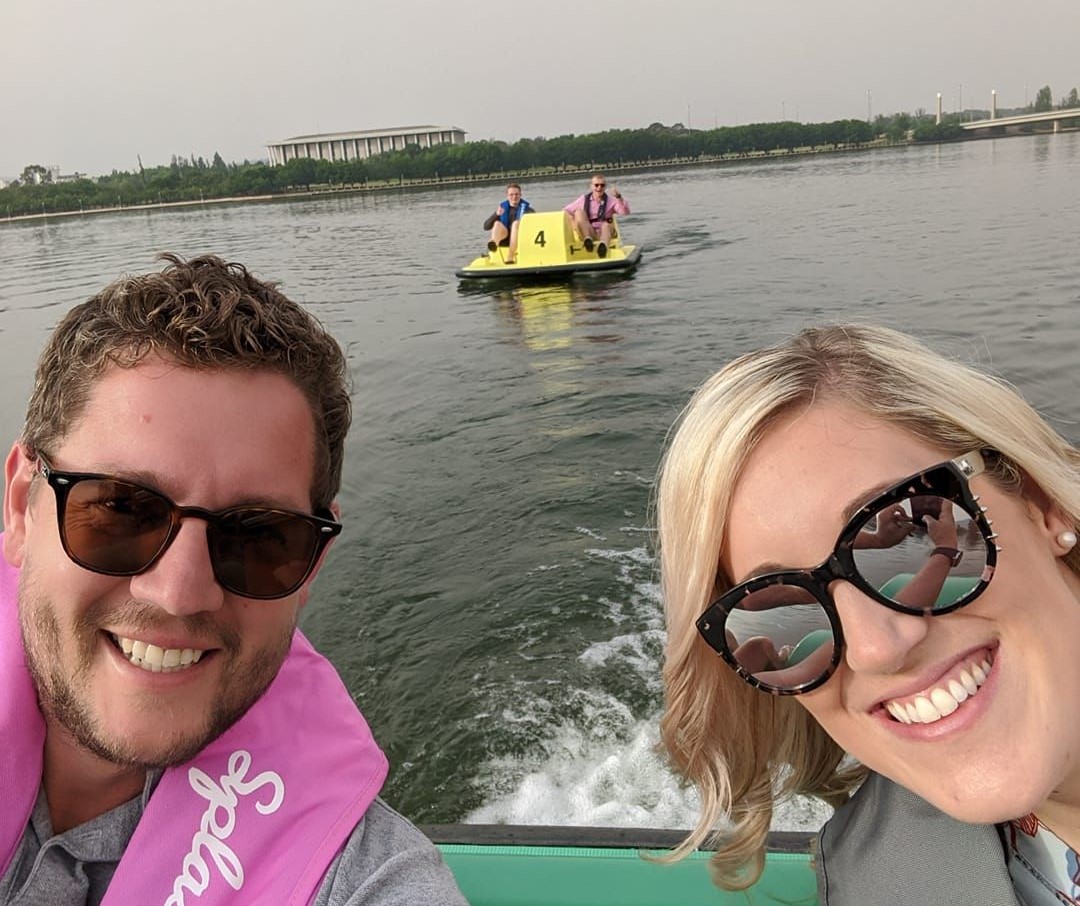 two people in a boat being followed by a paddle boat 