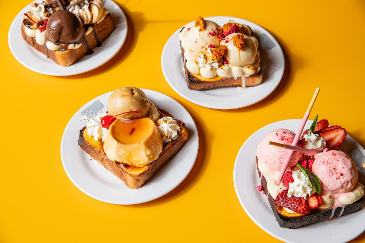Plates of toast loaded with icecream and other sweets on a bright yellow background