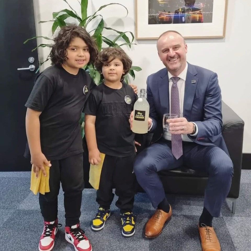 Yusuf and Noah pose with Andrew Bar, who holds a glass of lemonade. 