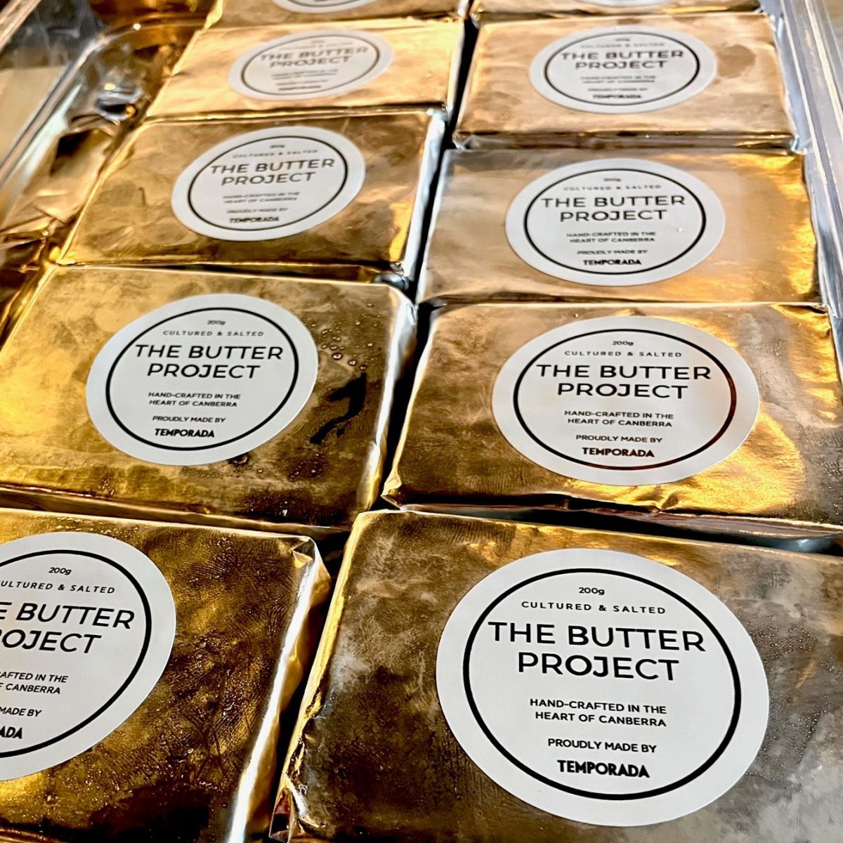 Blocks of foil wrapped butter with stickers reading 'the butter project'