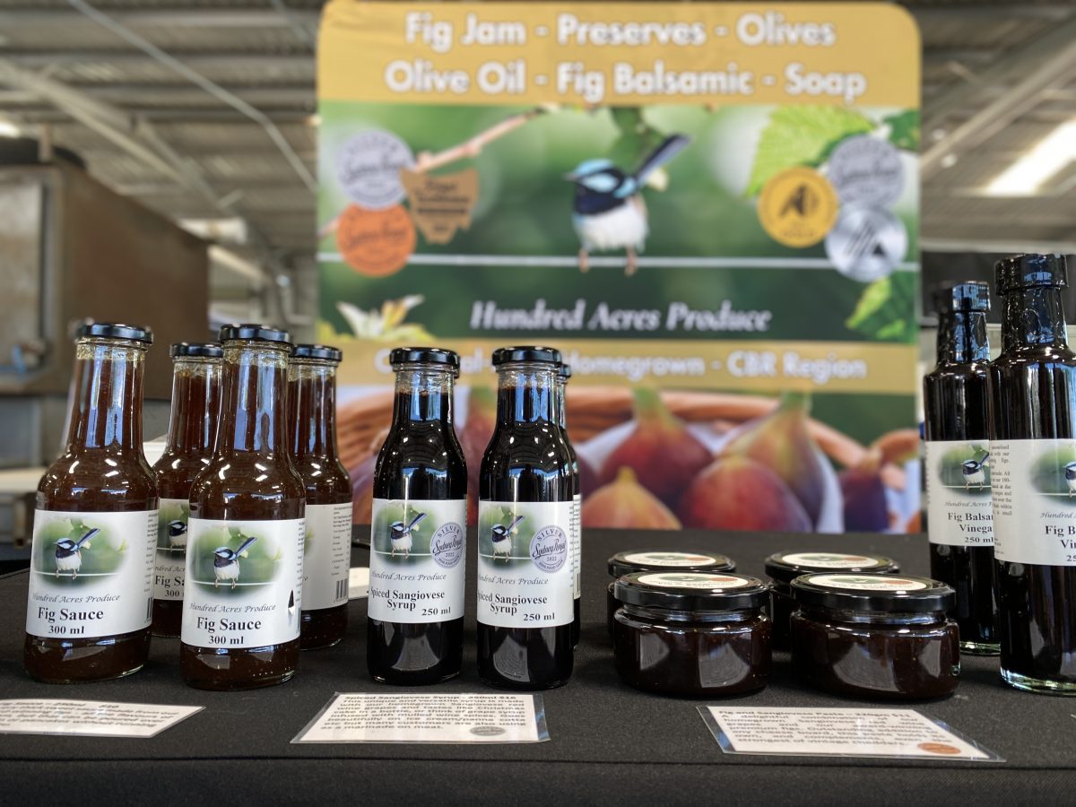 Fig products in bottles with Hundred Acres Produce Banner behind.