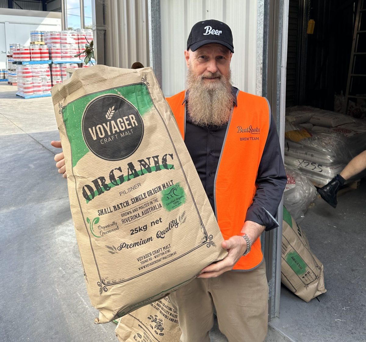 Peter holding a bag of barley outside a warehouse.