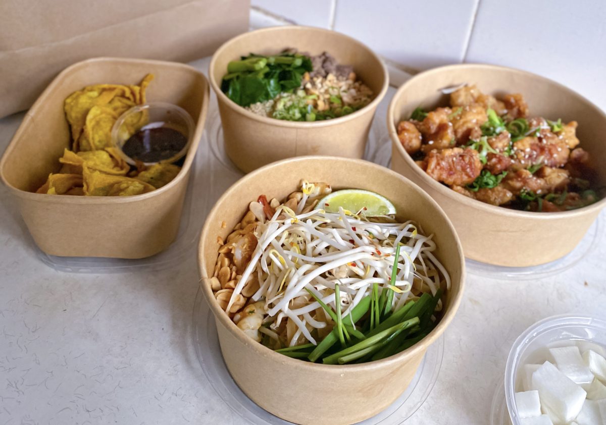 Four cardboard takeaway containers with yummy looking food.