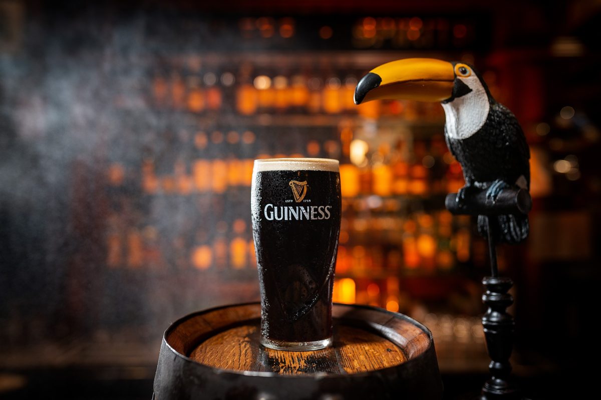 A glass of Guinness next to a bird