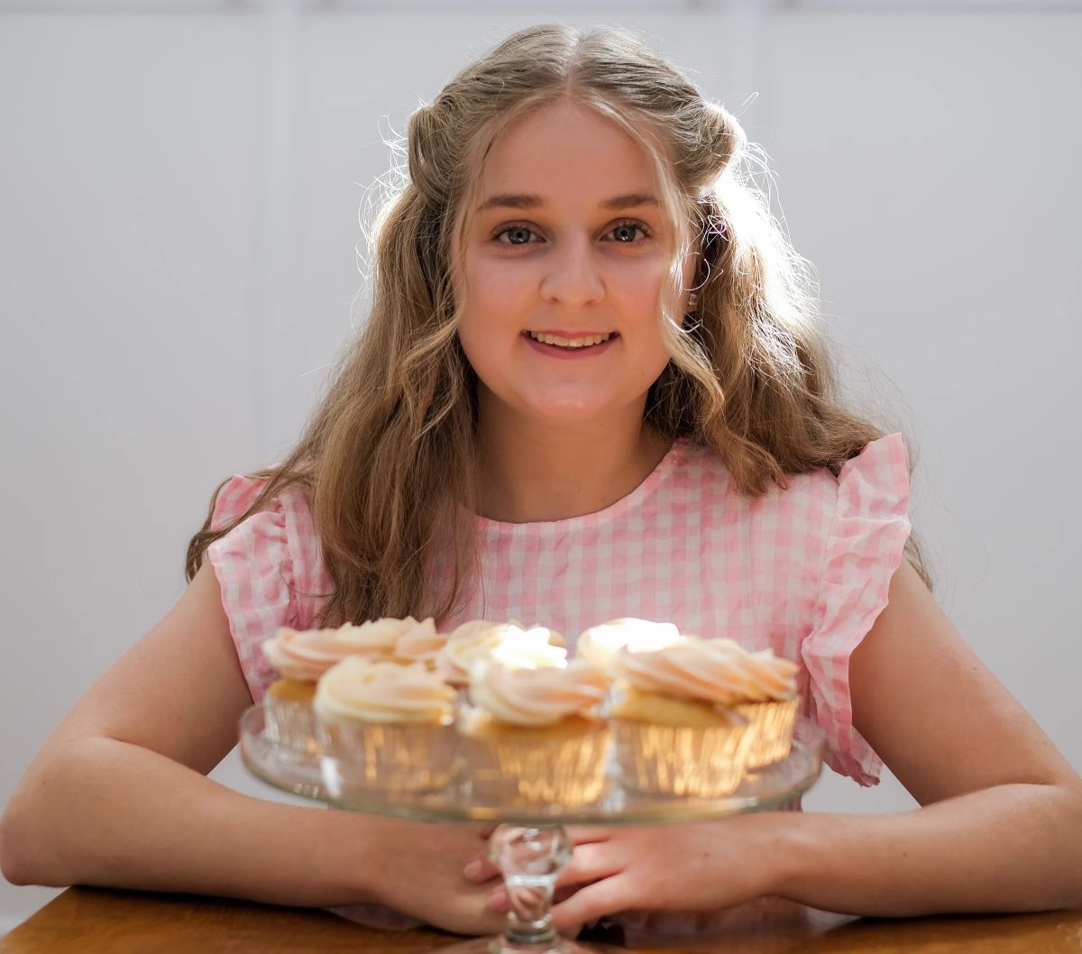 A young woman holding a dish of cupcakes