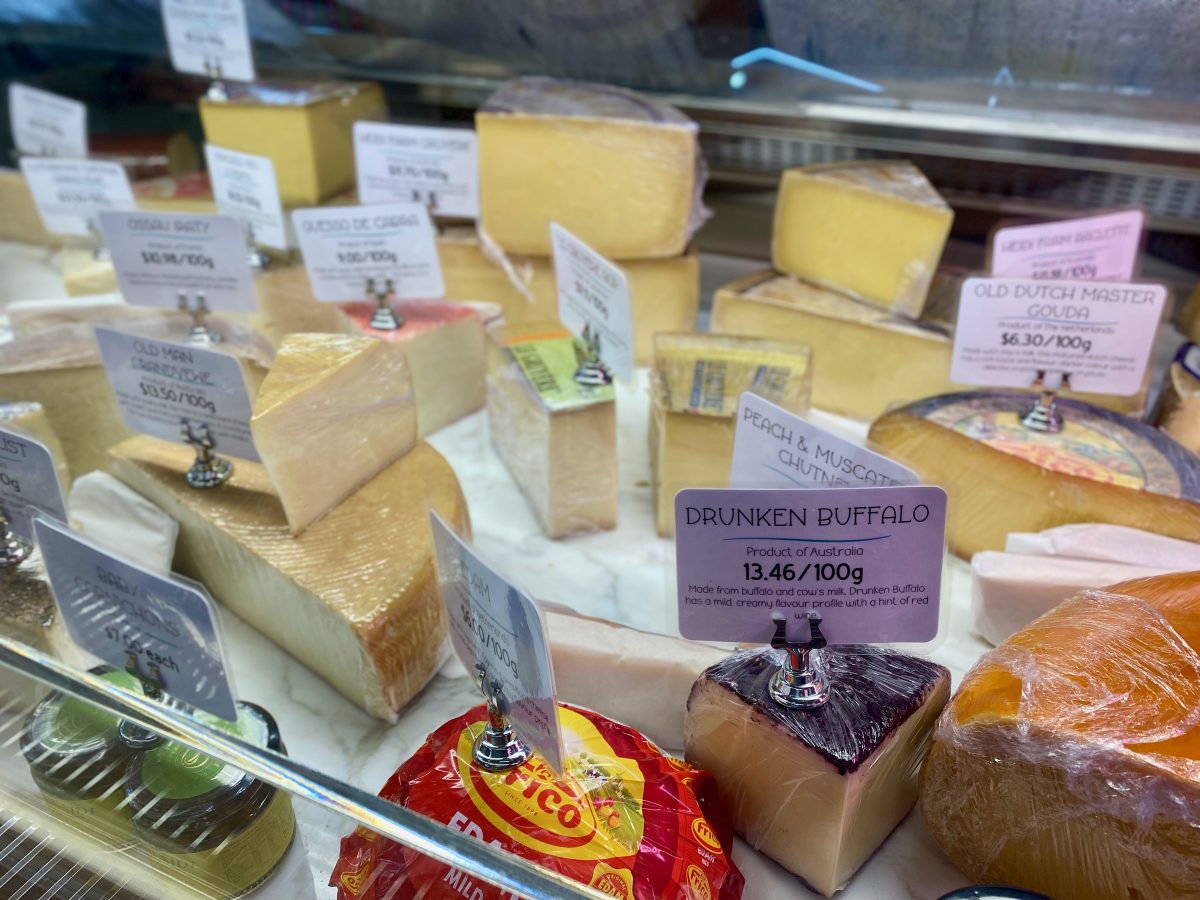 Cabinet full of different cheeses. In focus is a sign reading "Drunken Buffalo".